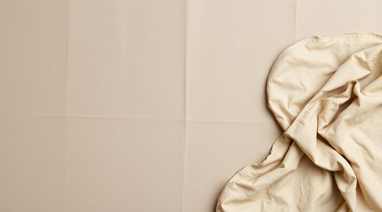 Warm taupe washed linen laid flat, with soft folds gathered at the right edge